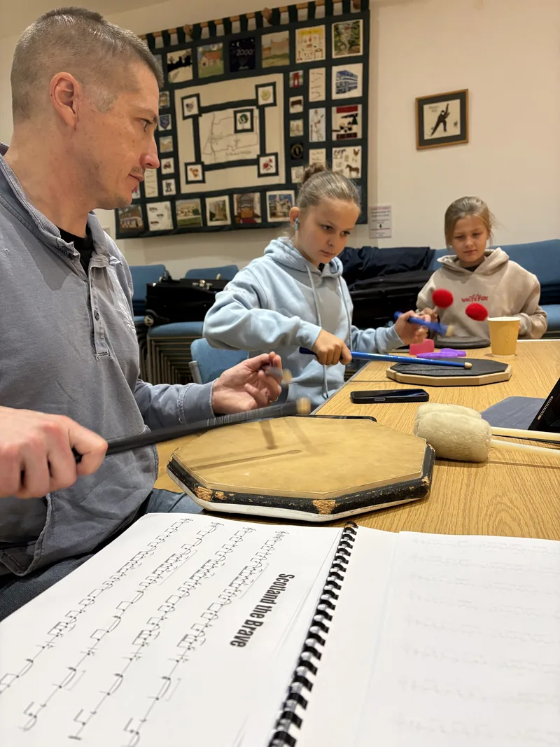 Learners practising drumming on practice pads at a band session